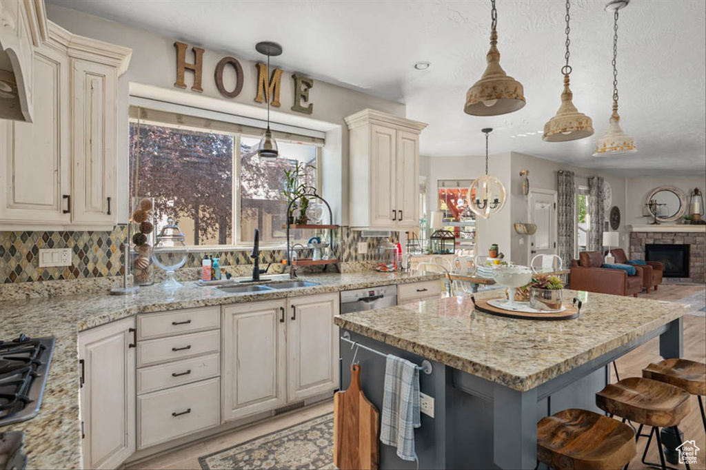 Kitchen featuring a kitchen bar, backsplash, cream cabinetry, and open floor plan