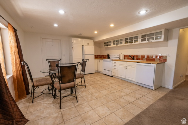 Kitchen featuring white appliances, recessed lighting, white cabinetry, glass insert cabinets, and light tile patterned floors