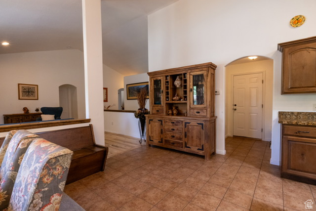 Living area with arched walkways, light tile patterned floors, high vaulted ceiling, and recessed lighting
