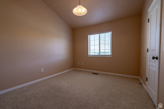 Carpeted spare room with baseboards and lofted ceiling