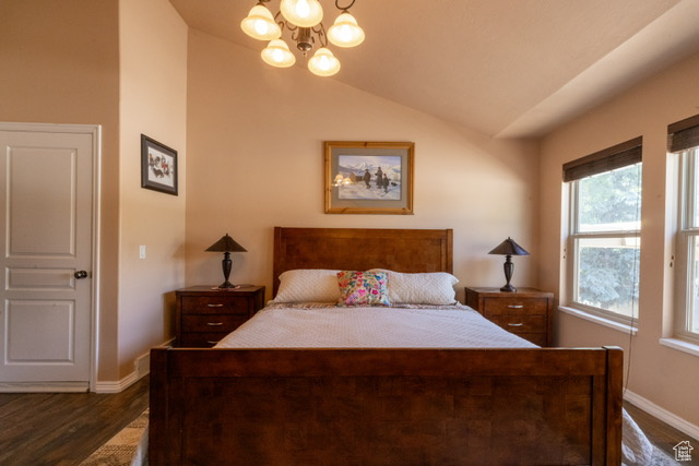 Bedroom featuring a chandelier, dark wood finished floors, and lofted ceiling