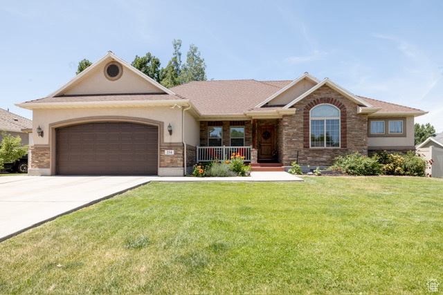 Single story home featuring concrete driveway, a garage, stucco siding, a front yard, and a porch