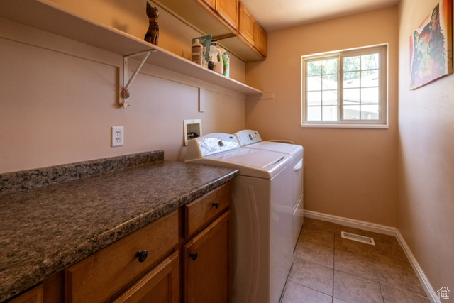 Washroom featuring separate washer and dryer, cabinet space, and light tile patterned floors
