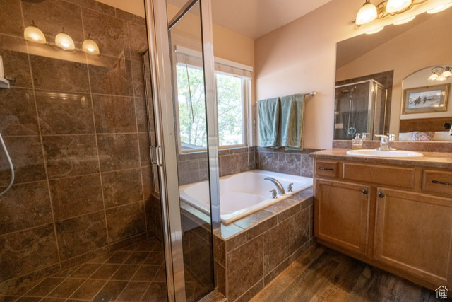 Bathroom with vanity, a stall shower, a bath, and wood finished floors