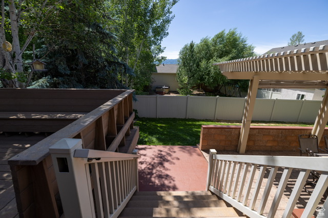 Wooden terrace with a fenced backyard and a patio