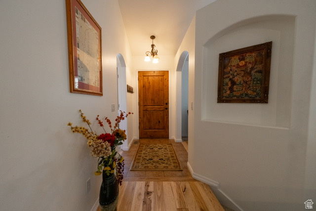 Corridor featuring arched walkways and wood finished floors