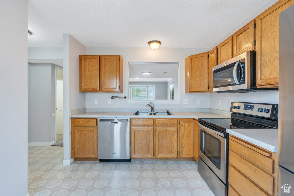 Kitchen featuring stainless steel appliances, light countertops, light flooring, and brown cabinetry