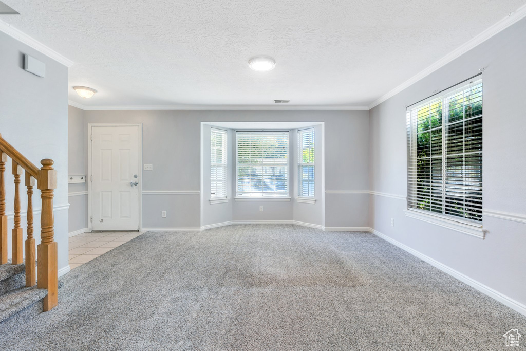 Carpeted spare room with stairs, ornamental molding, and a textured ceiling