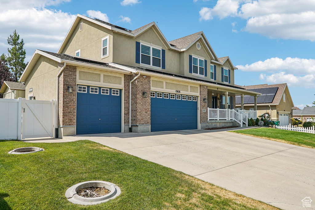 View of front facade featuring covered porch, concrete driveway, stucco siding, an attached garage, and a gate