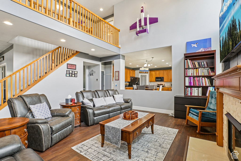 Living area with a high ceiling, recessed lighting, hardwood / wood-style floors, stairs, and a fireplace with flush hearth