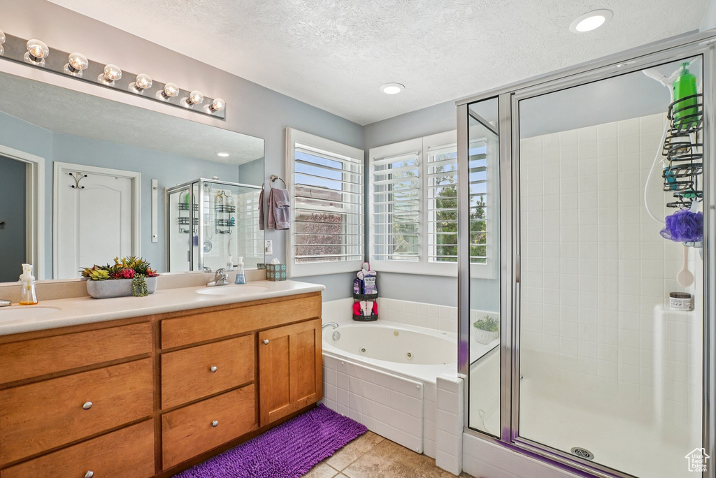 Full bath with a stall shower, double vanity, a textured ceiling, a tub with jets, and tile patterned flooring