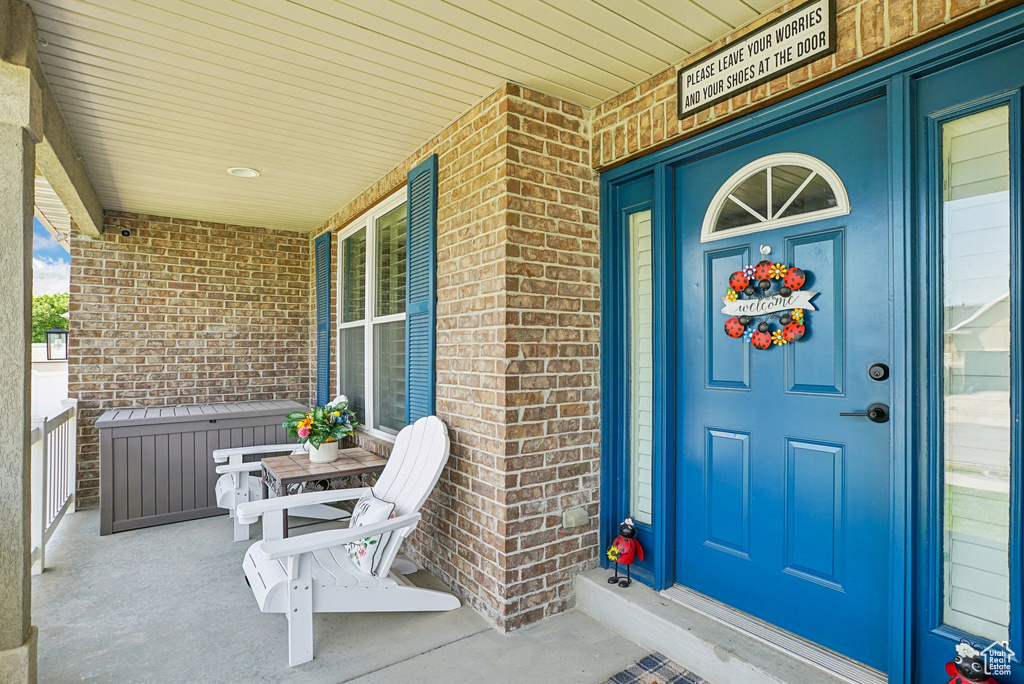 View of exterior entry with a porch and brick siding