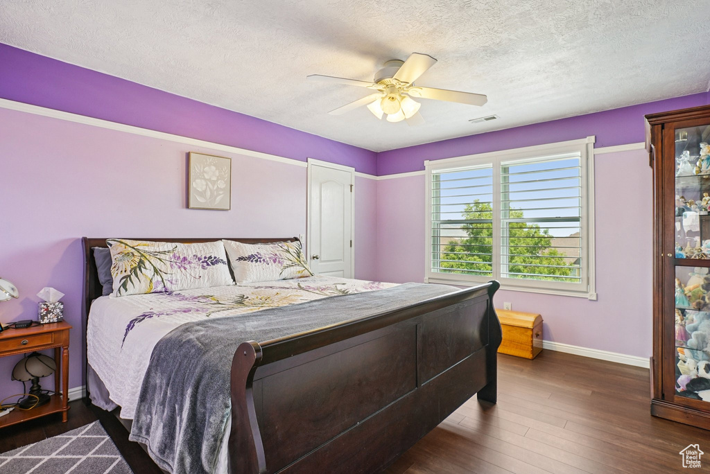 Bedroom featuring a textured ceiling, a ceiling fan, and wood finished floors