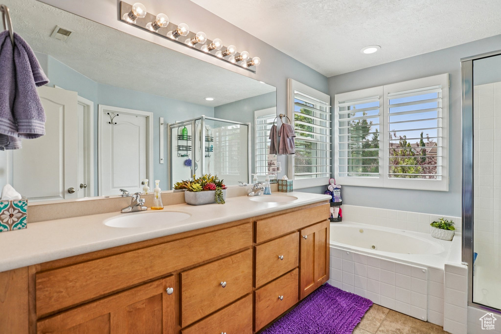 Full bathroom featuring a stall shower, double vanity, a tub with jets, a textured ceiling, and tile patterned floors