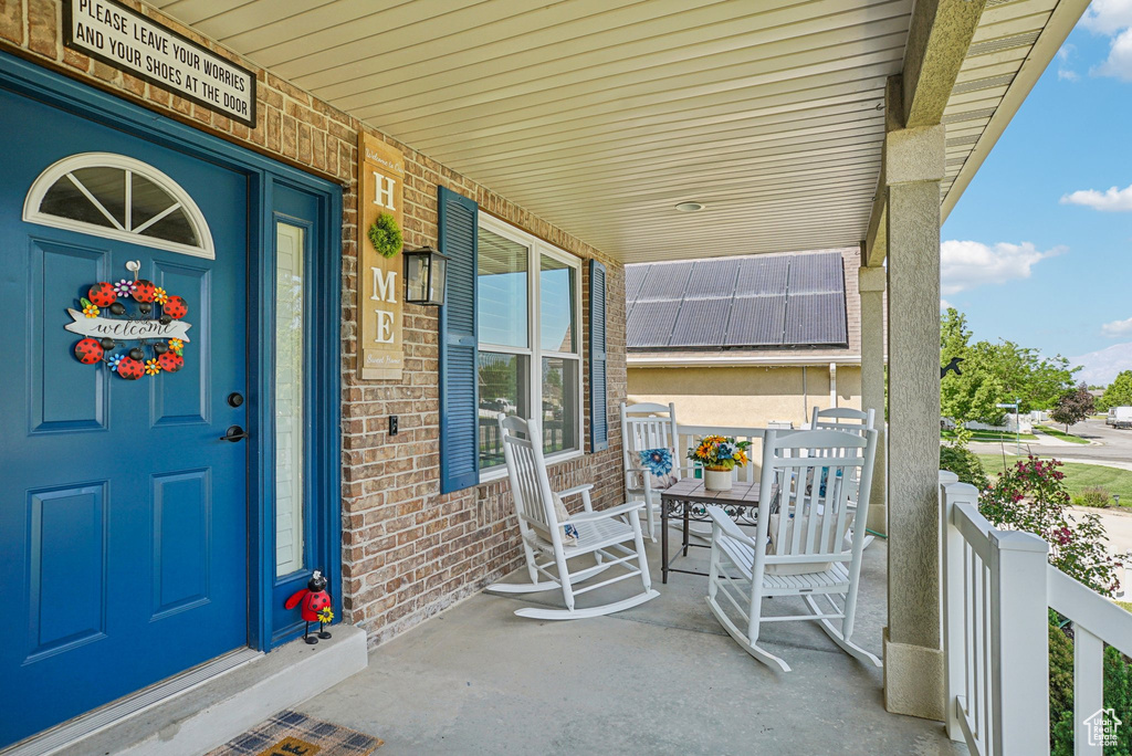 Doorway to property with covered porch and brick siding