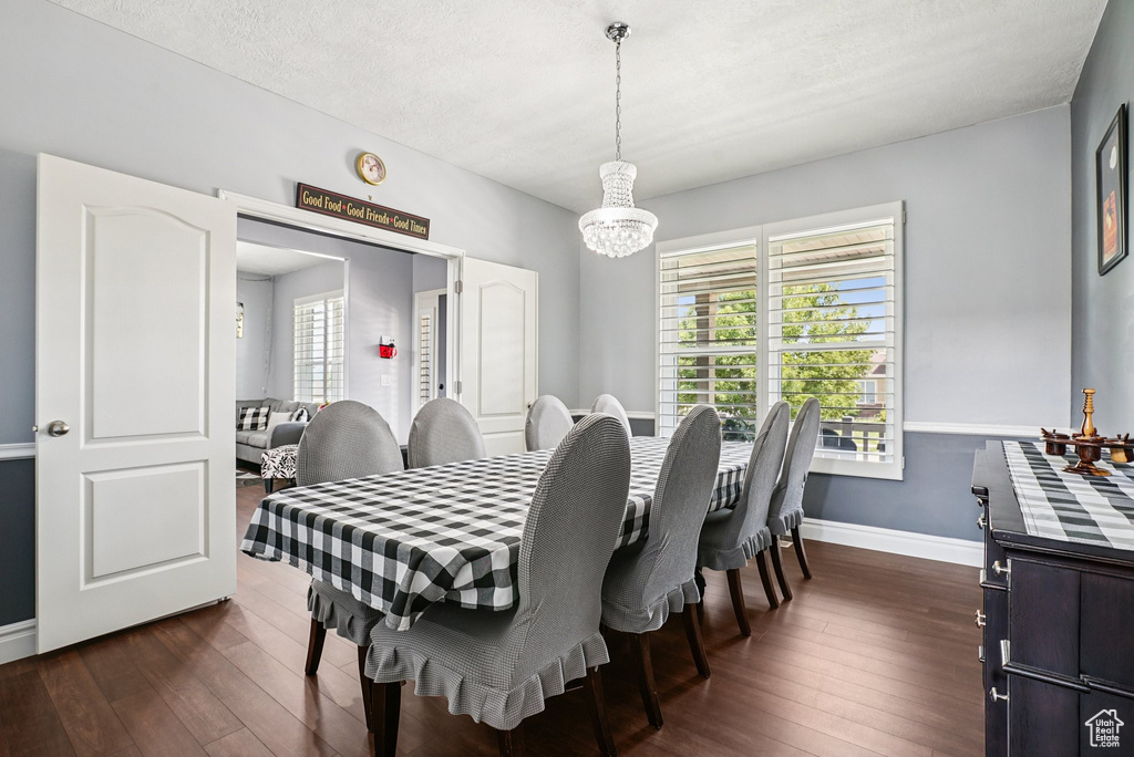 Dining area with a chandelier and dark wood-type flooring