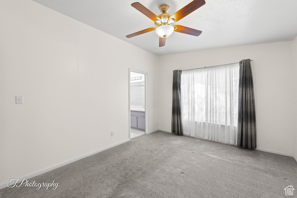 Carpeted empty room with ceiling fan and baseboards