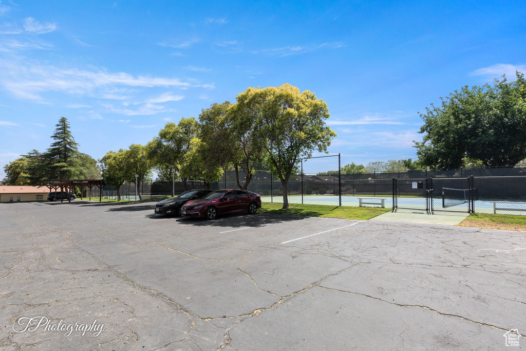 Uncovered parking lot featuring a tennis court