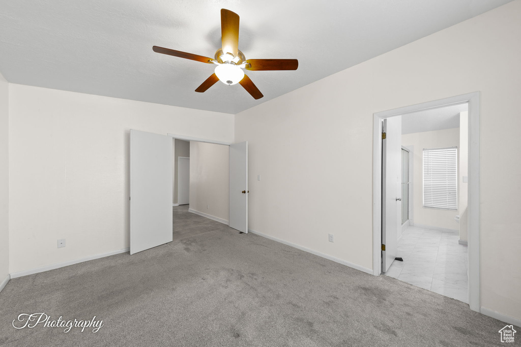 Unfurnished bedroom featuring carpet, ensuite bathroom, and ceiling fan
