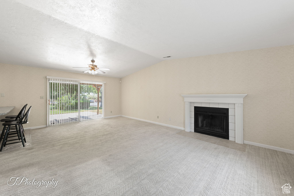 Unfurnished living room featuring ceiling fan, light carpet, a fireplace, and vaulted ceiling
