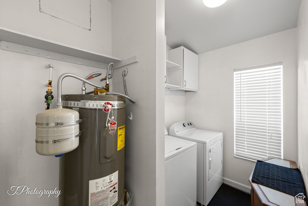 Washroom featuring water heater, cabinet space, and washer and dryer