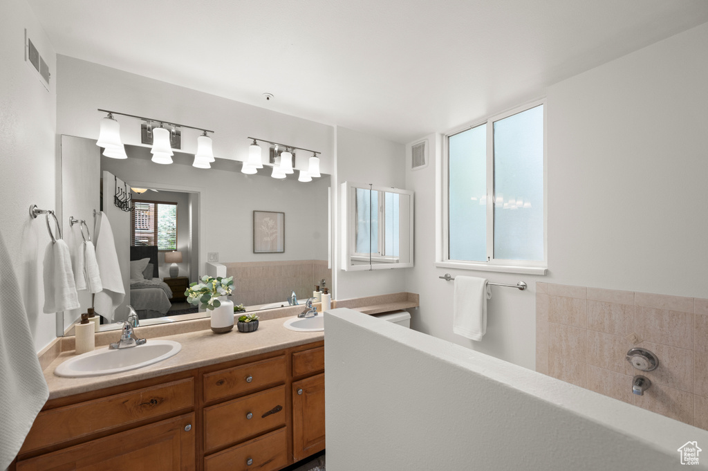 Bathroom with connected bathroom, double vanity, and a garden tub