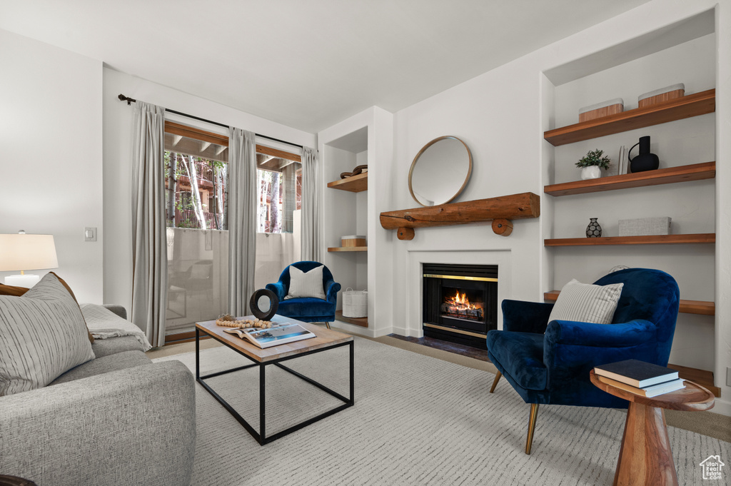 Living area with built in features and a fireplace with flush hearth
