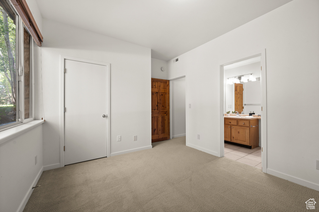 Unfurnished bedroom featuring light colored carpet and ensuite bath