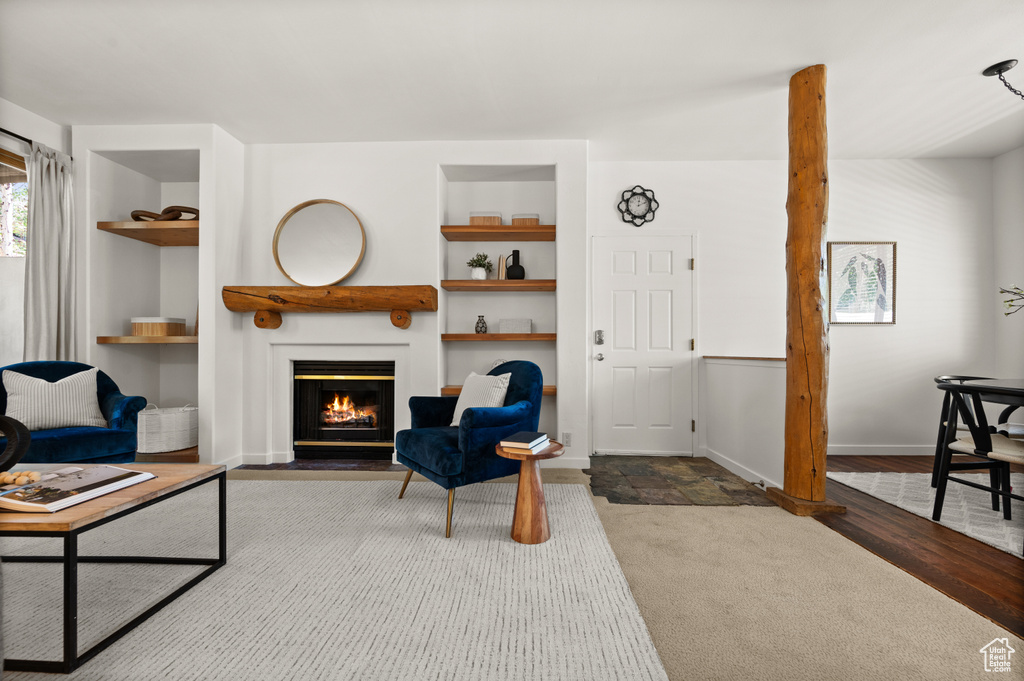 Living room featuring built in features, a fireplace with flush hearth, and carpet floors