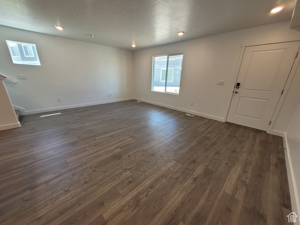 Unfurnished room with dark wood-type flooring, stairway, recessed lighting, and a textured ceiling