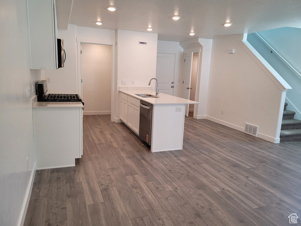 Kitchen with appliances with stainless steel finishes, a peninsula, dark wood-style floors, white cabinetry, and light countertops