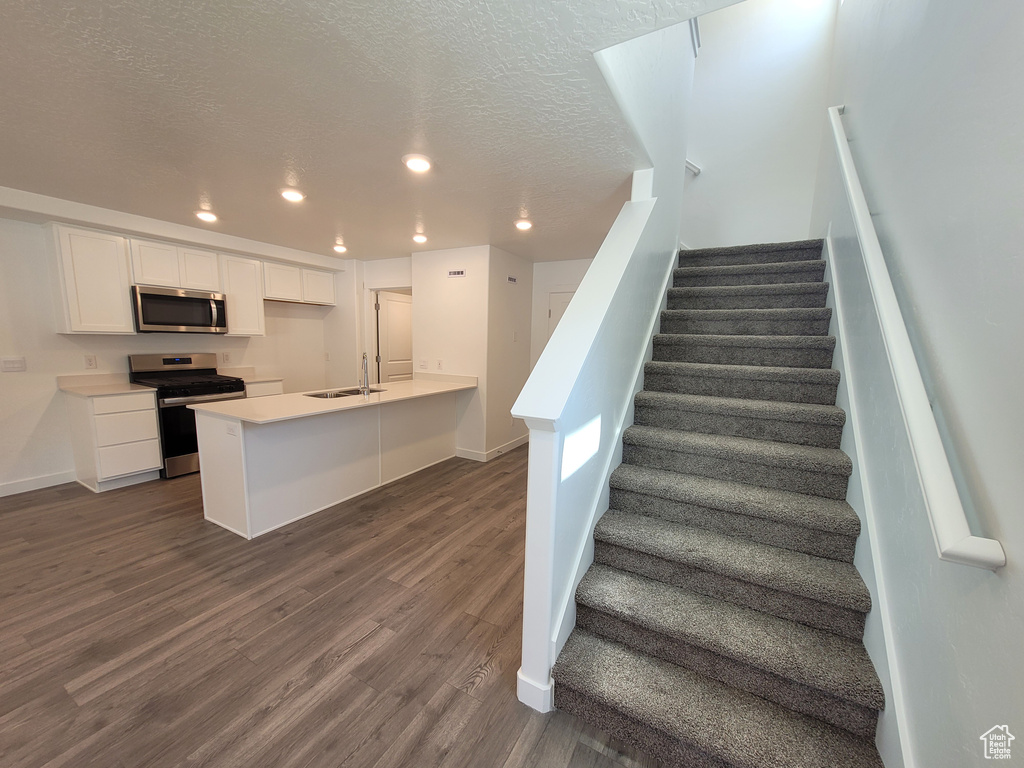 Staircase featuring recessed lighting, wood finished floors, and a textured ceiling