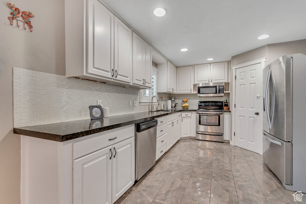 Kitchen featuring appliances with stainless steel finishes, white cabinetry, backsplash, and recessed lighting