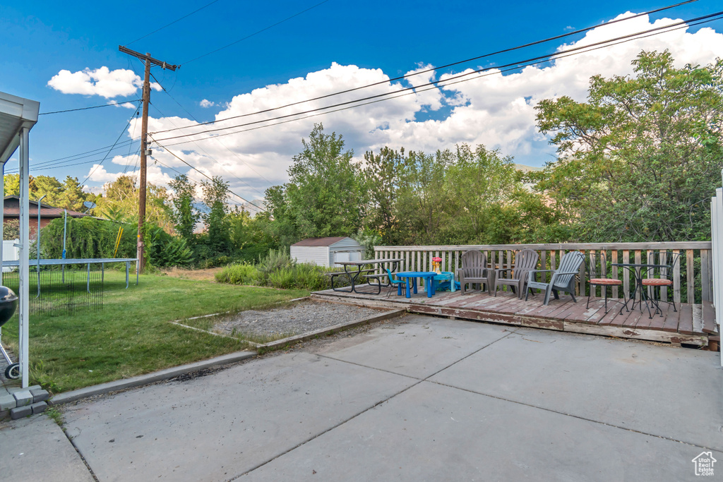 View of patio / terrace with a trampoline, a storage unit, and a deck