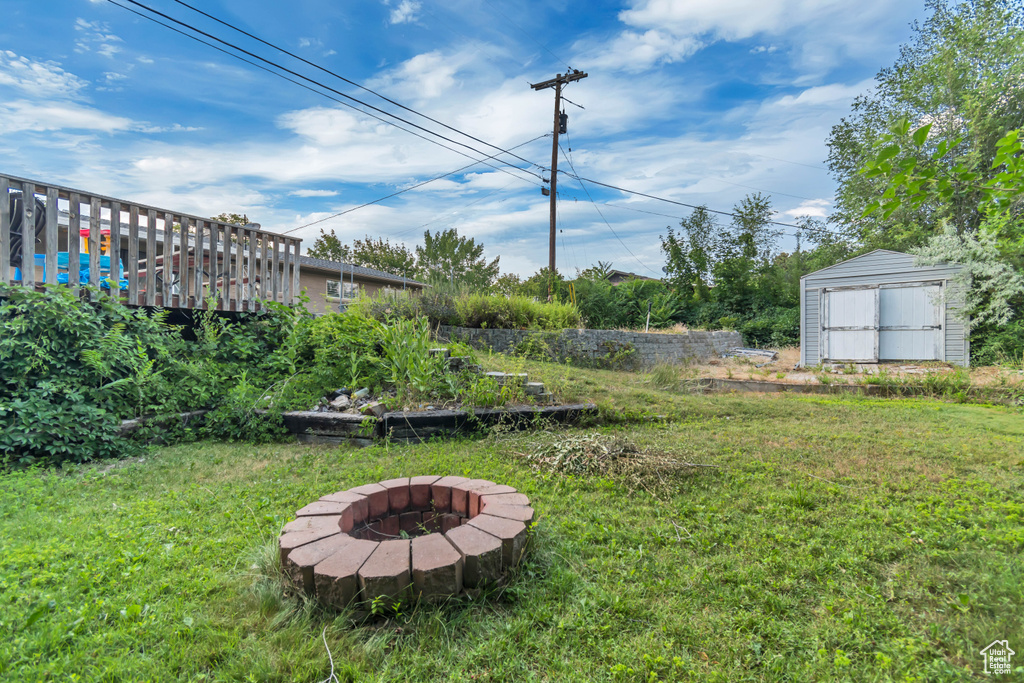 View of green lawn with a fire pit and a shed