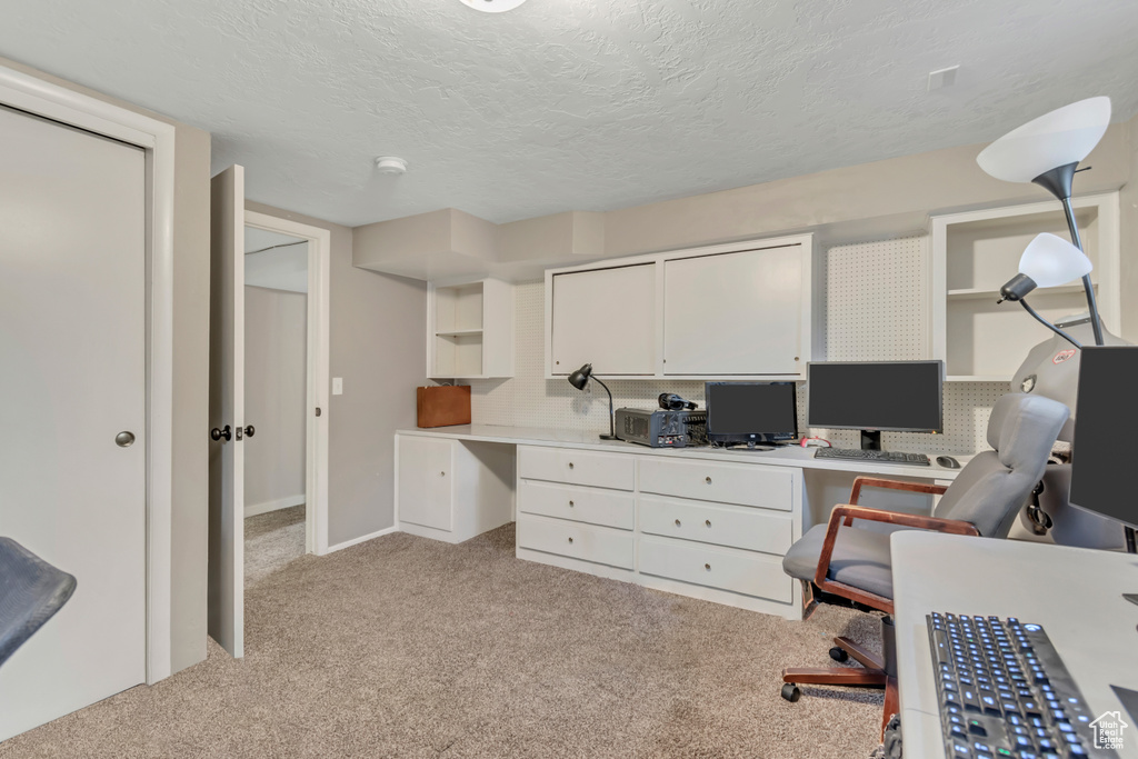 Office featuring light colored carpet, a textured ceiling, and built in desk