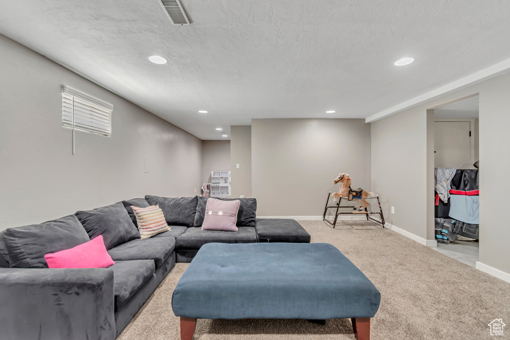Living area with light carpet, recessed lighting, and a textured ceiling
