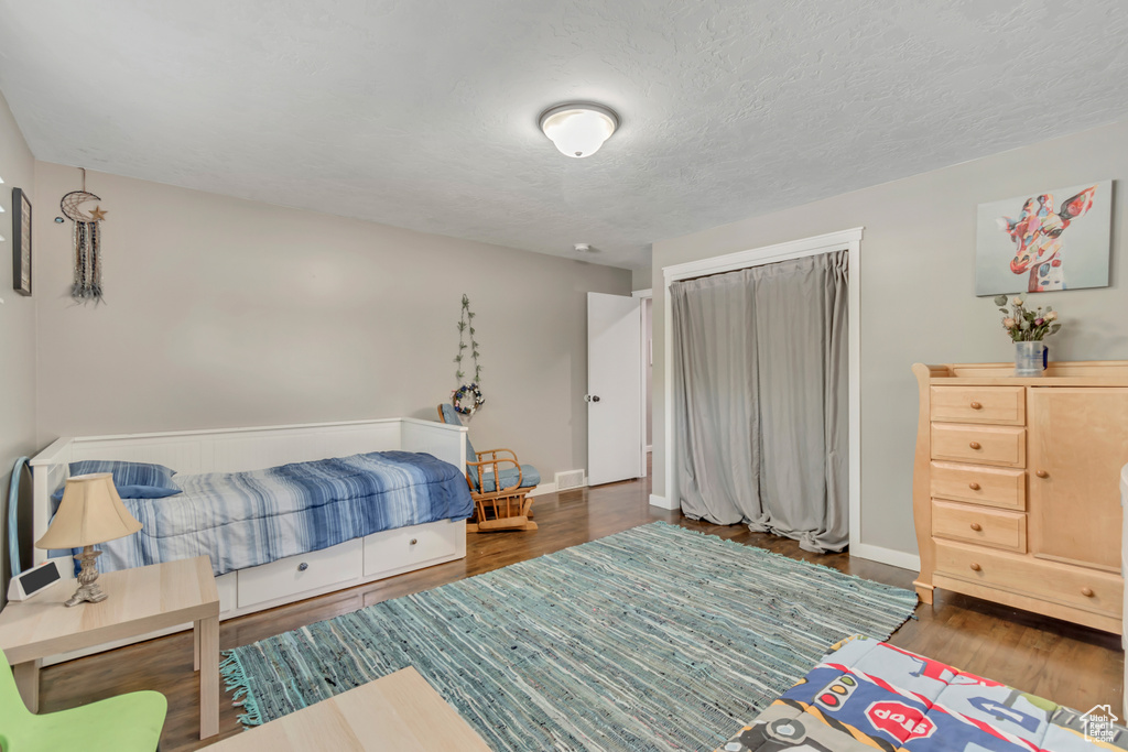 Bedroom with wood finished floors, a closet, and a textured ceiling