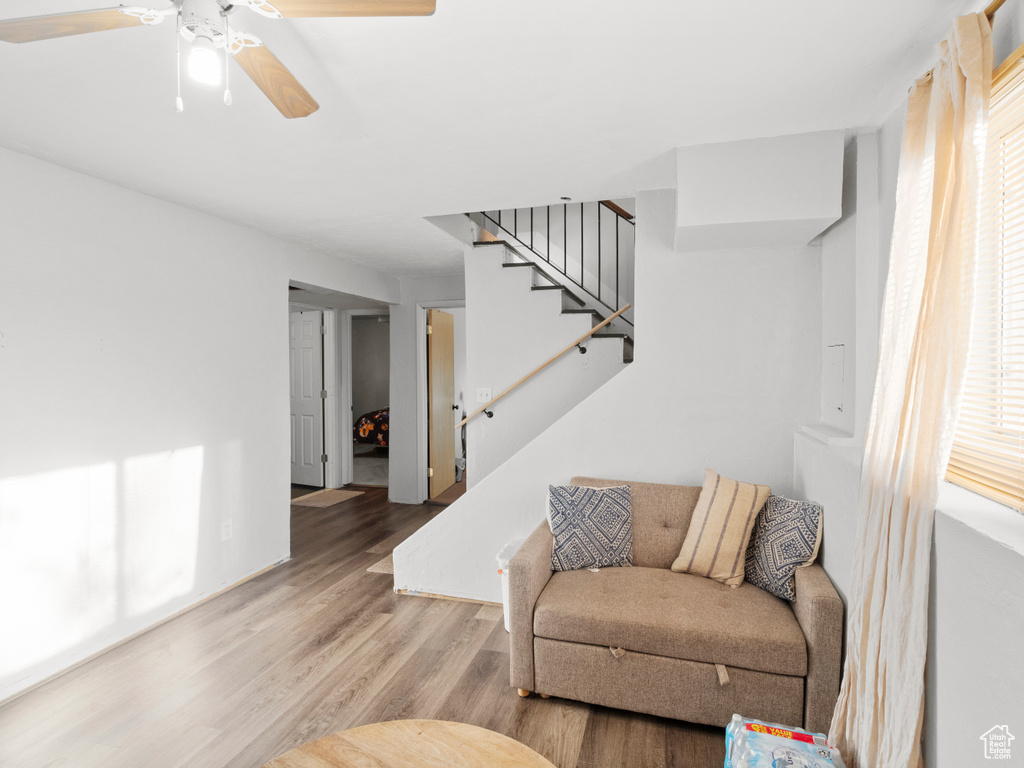 Living area with stairway, wood finished floors, and a ceiling fan