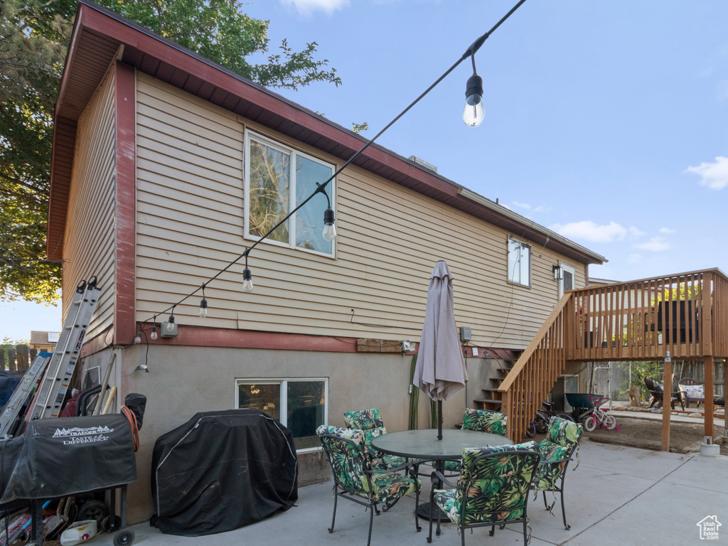 Back of property with stairway, a patio, outdoor dining area, and a deck