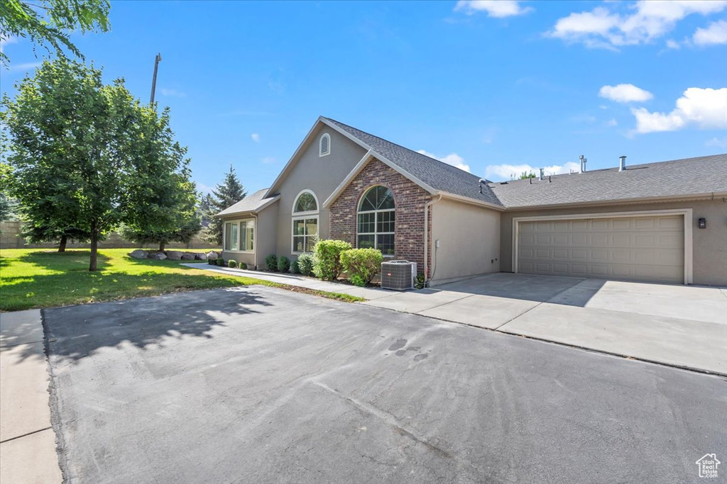 View of front of property featuring driveway, stucco siding, a garage, a front lawn, and a shingled roof