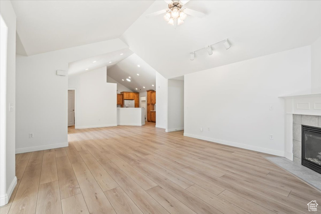 Unfurnished living room with a tile fireplace, vaulted ceiling, recessed lighting, ceiling fan, and light wood-style floors
