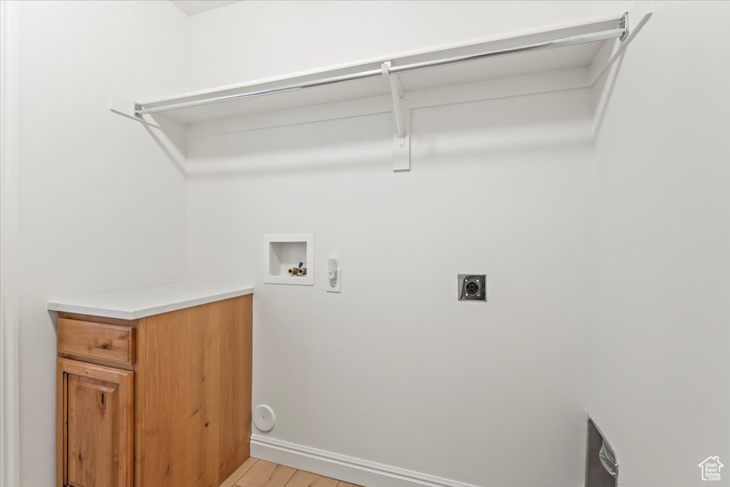 Washroom with hookup for an electric dryer, hookup for a washing machine, and light wood-style floors