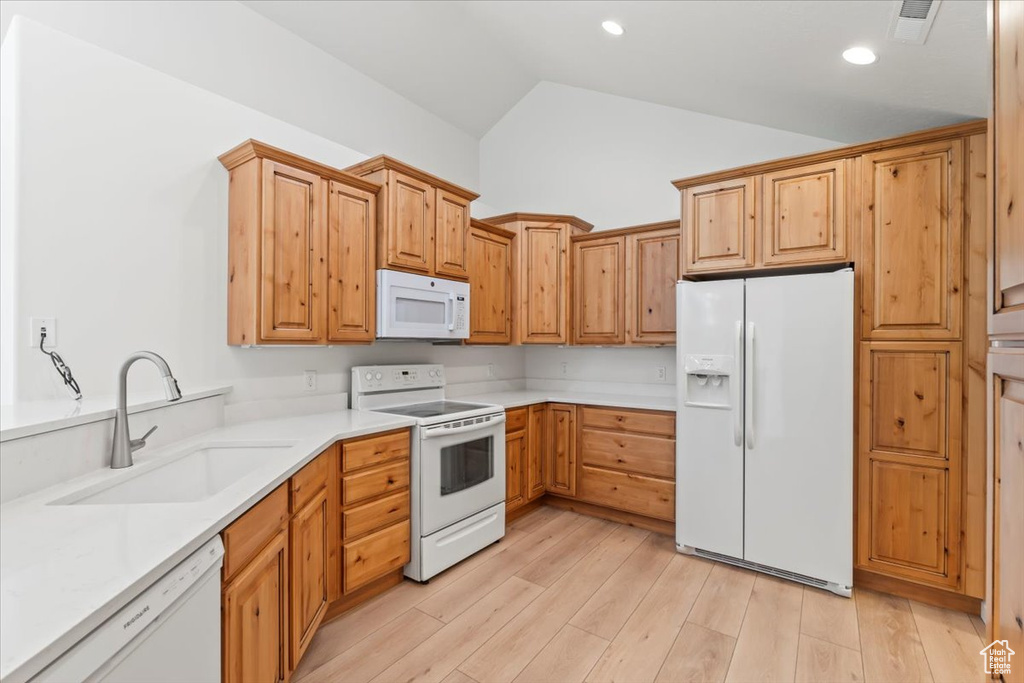 Kitchen featuring white appliances, lofted ceiling, light countertops, light wood-style floors, and recessed lighting