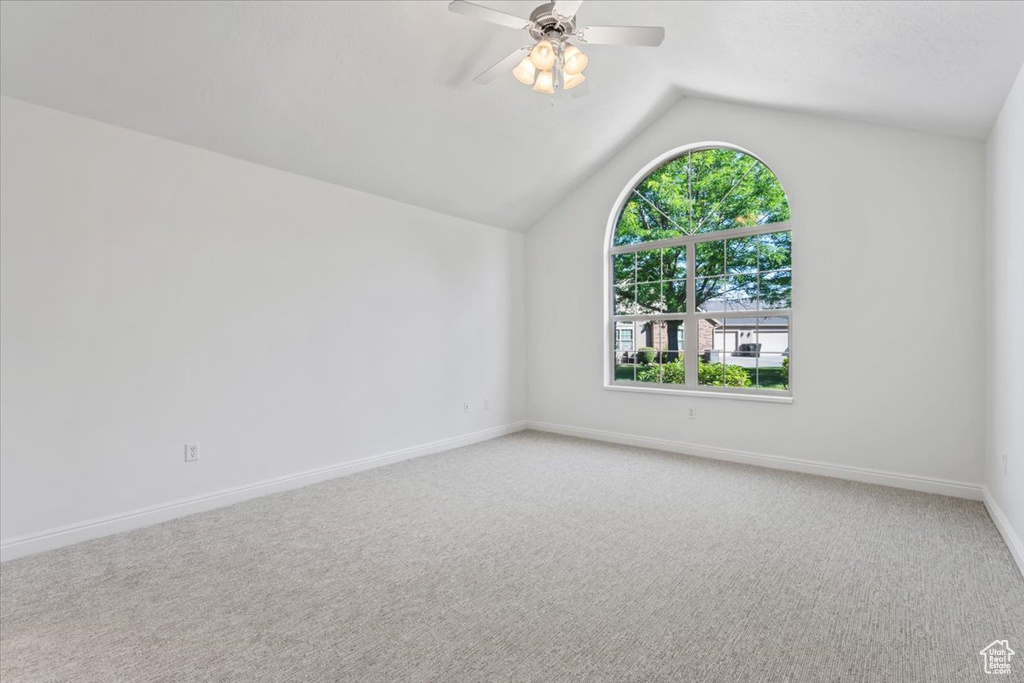 Additional living space with vaulted ceiling, light colored carpet, and ceiling fan
