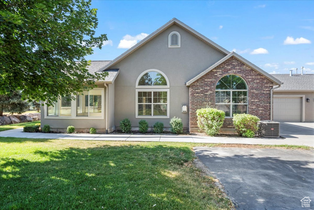 View of front of house with stucco siding, a front lawn, an attached garage, and brick siding