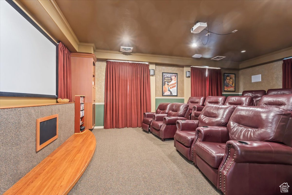 Carpeted home theater with crown molding and a fireplace