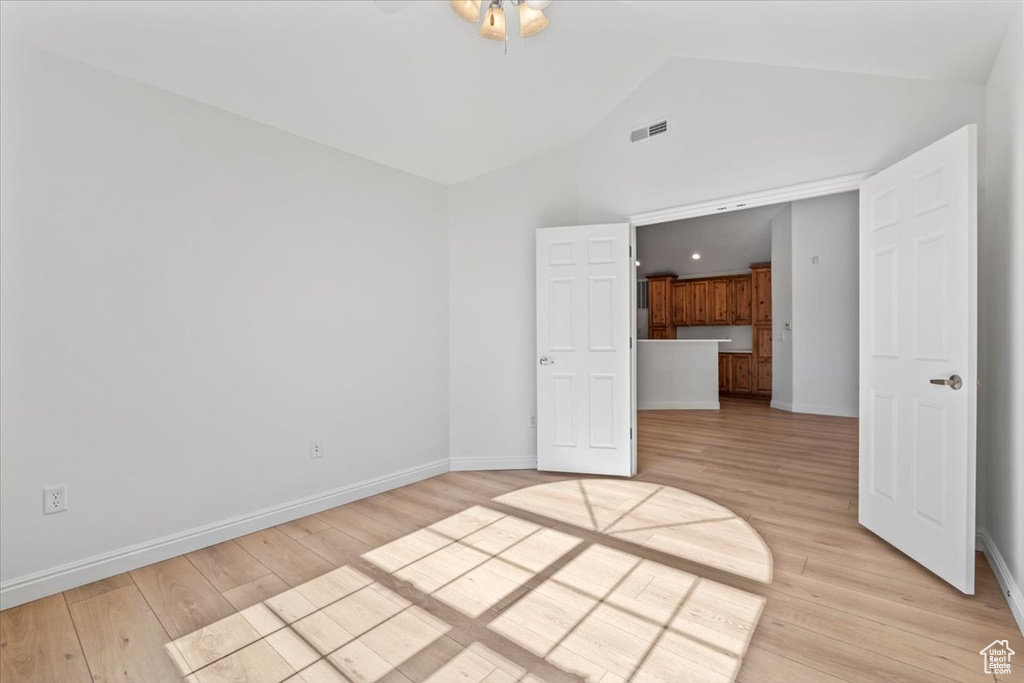 Empty room with light wood-style flooring, a ceiling fan, and high vaulted ceiling