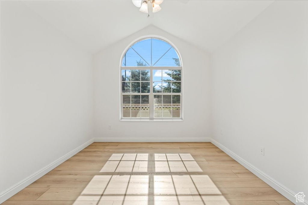 Empty room with lofted ceiling, light wood finished floors, and ceiling fan