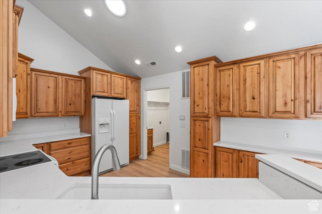Kitchen featuring white appliances, light wood finished floors, lofted ceiling, light countertops, and recessed lighting